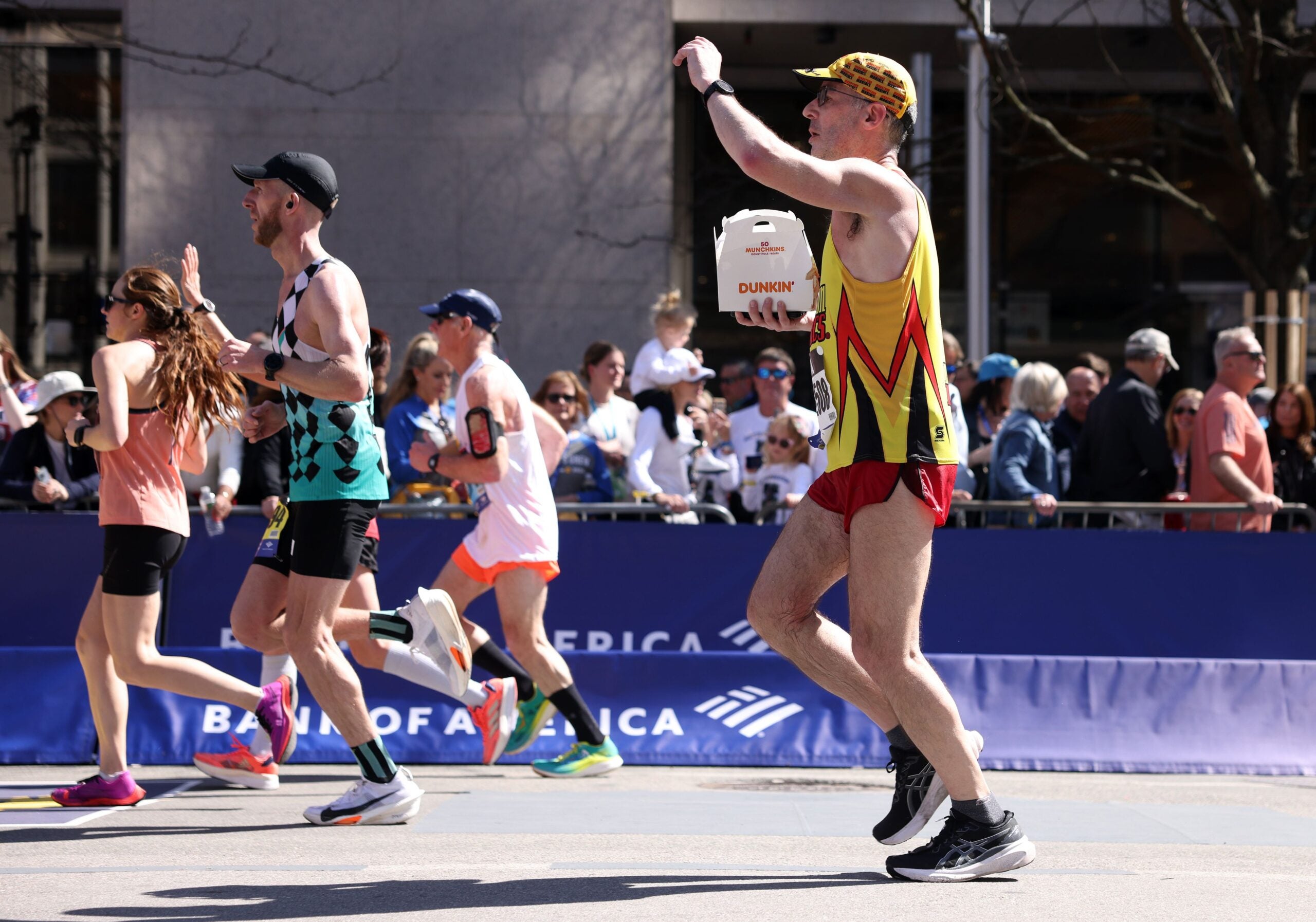 A runner carried a box of munchkin’s during the Boston Marathon on Monday, April 15, 2024.