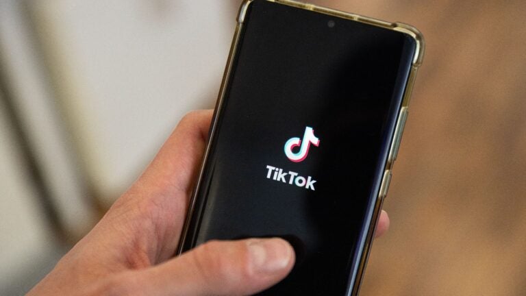 This photograph taken on April 19, 2024 shows a man holding a smartphone displaying the logo of Chinese social media platform TikTok.