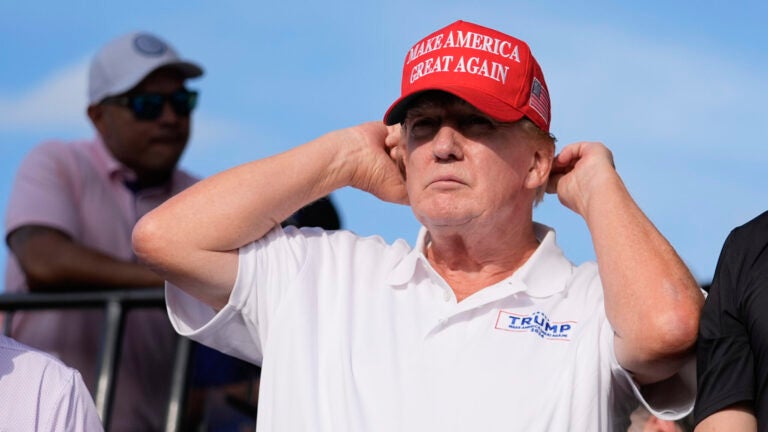 Republican presidential candidate former President Donald Trump adjusts his cap.