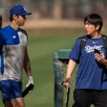 Los Angeles Dodgers' Shohei Ohtani walks with interpreter Ippei Mizuhara at batting practice during spring training baseball workouts in Phoenix.