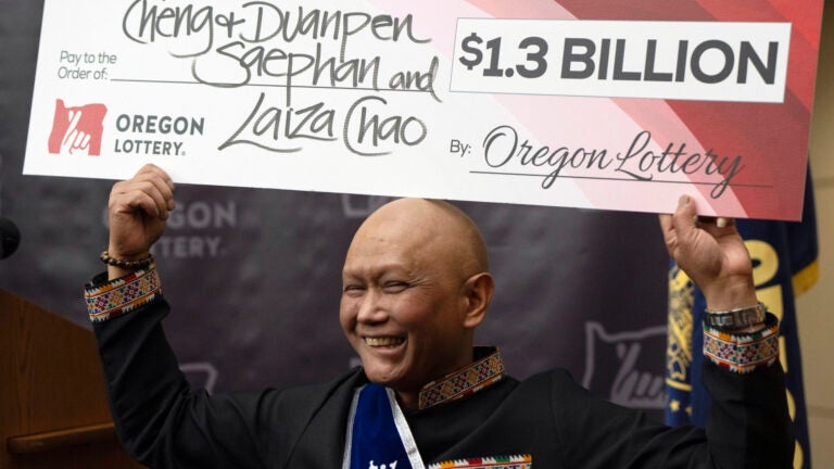 Cheng "Charlie" Saephan holds a check above his head at the Oregon Lottery headquarters.