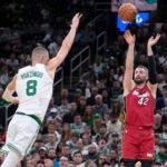 Miami Heat forward Kevin Love (42) shoots at the basket as Boston Celtics center Kristaps Porzingis (8) defends in the second half of Game 1 of an NBA basketball first-round playoff series, Sunday, April 21, 2024, in Boston.