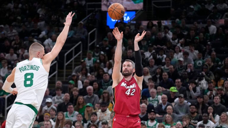 Miami Heat forward Kevin Love (42) shoots at the basket as Boston Celtics center Kristaps Porzingis (8) defends in the second half of Game 1 of an NBA basketball first-round playoff series, Sunday, April 21, 2024, in Boston.