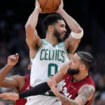 Boston Celtics forward Jayson Tatum, center, passes the ball over Miami Heat forward Caleb Martin, right, in the second half of Game 1 of an NBA basketball first-round playoff series, Sunday, April 21, 2024, in Boston.