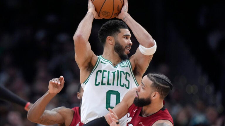 Boston Celtics forward Jayson Tatum, center, passes the ball over Miami Heat forward Caleb Martin, right, in the second half of Game 1 of an NBA basketball first-round playoff series, Sunday, April 21, 2024 , in Boston.