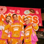 Ben Afflect, Tom Brady, and Matt Damon in orange and pink tracksuits from their Super Bowl commercial for Dunkin'.