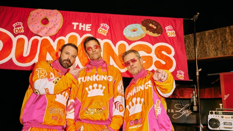 Ben Afflect, Tom Brady, and Matt Damon in orange and pink tracksuits from their Super Bowl commercial for Dunkin'.