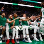 The Celtics Jaylen Brown is congratulated as he heads for the bench to sit with, left to right, Jayson Tatum, Derrick White, Al Horford, Kristaps Porzingis, and Jrue Holiday during the fourth quarter.
