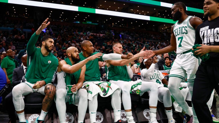 The Celtics Jaylen Brown is congratulated as he heads for the bench to sit with, left to right, Jayson Tatum, Derrick White, Al Horford, Kristaps Porzingis, and Jrue Holiday during the fourth quarter.