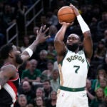 Celtics guard Jaylen Brown takes a shot over Portland Trail Blazers center Deandre Ayton, left, during the first half.