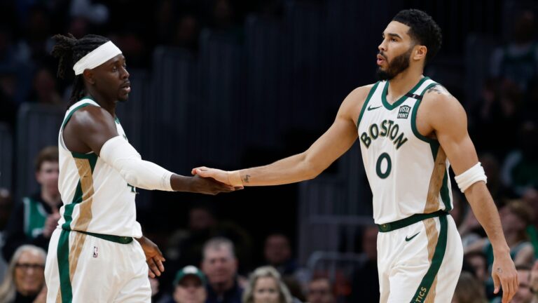 Boston Celtics' Jayson Tatum (0) and Jrue Holiday, center, react behind teammate Kristaps Porzingis during the second half of an NBA basketball game against the Washington Wizards, Friday, Feb. 9, 2024, in Boston.