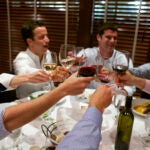 A group of diners at a table with food and wine.