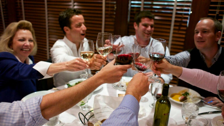 A group of diners at a table with food and wine.