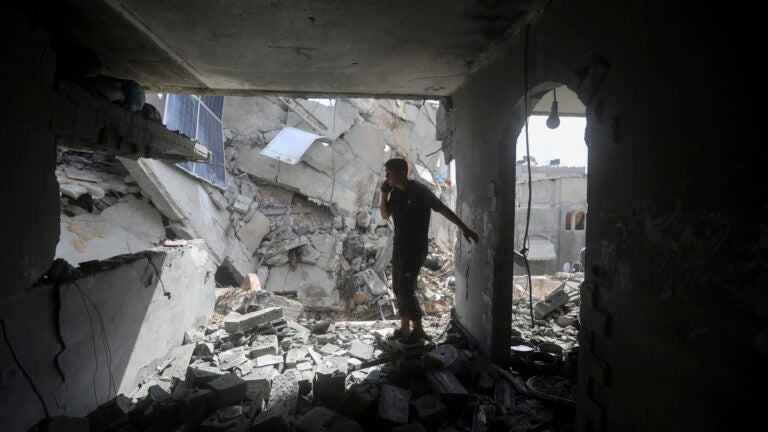 Palestinians look at the destruction after an Israeli strike on residential building in Rafah.