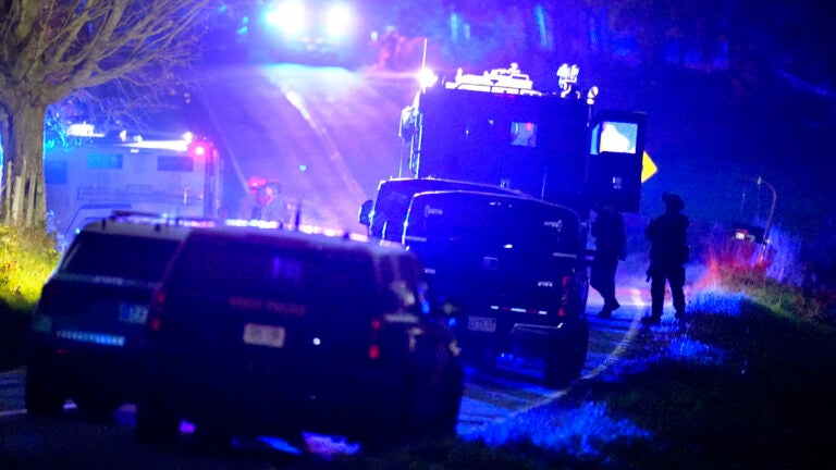 Law enforcement officers stand near armored and tactical vehicles in Bowdoin, Maine.