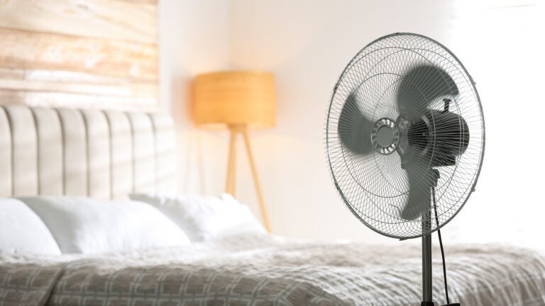 Modern electric fan in bedroom. Space for text