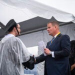 Billionaire Robert Hale, right, with a graduate student onstage at the graduation ceremony Thursday, May 16, 2024, in Dartmouth, Mass. Hale gifted graduates at the University of Massachusetts Dartmouth each with $1,000., with the condition that they give $500 away.