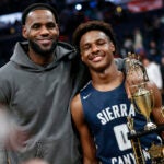 LeBron James, left, poses with his son Bronny after Sierra Canyon beat Akron St. Vincent - St. Mary in a high school basketball game, Saturday, Dec. 14, 2019, in Columbus, Ohio. Bronny James, son of NBA superstar LeBron James, was hospitalized after going into cardiac arrest while participating in a practice at Southern California on Monday, July 24, 2023.