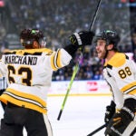 Boston Bruins left wing Brad Marchand (63) and right wing David Pastrnak (88) celebrate Marchand's overtime goal against the Toronto Maple Leafs in an NHL hockey game Saturday, Dec. 2, 2023, in Toronto.