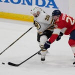 Boston Bruins defenseman Derek Forbort (28) and Florida Panthers center Carter Verhaeghe (23) go after the puck during the first period of an NHL hockey game, Wednesday, Nov. 22, 2023, in Sunrise, Fla.