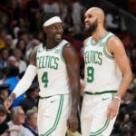 Boston Celtics guard Jrue Holiday (4) and Boston Celtics guard Derrick White (9) talk during the second half of an NBA basketball game against the Miami Heat, Thursday, Jan. 25, 2024, in Miami. The Celtics defeated the Heat 143-110.