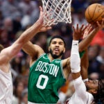 Celtics forward Jayson Tatum drives to the basket between Cavaliers forward Dean Wade and guard Darius Garland during the first half.
