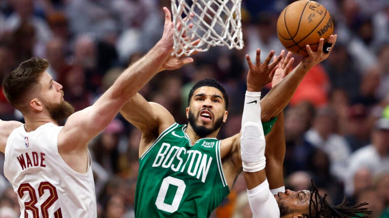 Celtics forward Jayson Tatum drives to the basket between Cavaliers forward Dean Wade and guard Darius Garland during the first half.