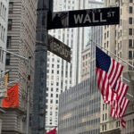 FILE - American flags hang from the front the New York Stock Exchange, right, in New York.