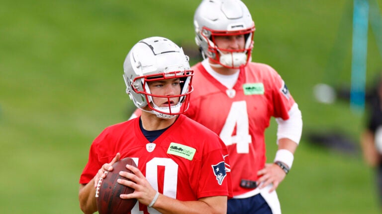 New England Patriots rookie quarterback Drake Maye (10) throws the ball as quarterback Bailey Zappe (4) looks on during OTAs at the Gillette Stadium practice field.