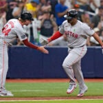 Boston Red Sox's Rafael Devers celebrates with third base coach Kyle Hudson after his two-run home run off Tampa Bay Rays starting pitcher Taj Bradley during the fourth inning.