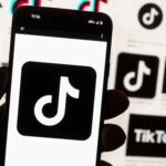 FILE - The TikTok logo is displayed on a mobile phone in front of a computer screen, Oct. 14, 2022, in Boston.