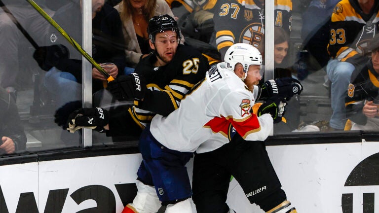 Boston Bruins defenseman Brandon Carlo (25) is checked into the boards by Florida Panthers center Sam Bennett (9) during third period action in game three of the Eastern Conference NHL second round Playoff game at TD Garden.
