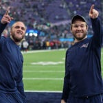 Steve Belichick (left) and his brother Brian Belichick (right), the sons of Patriots head coach Bill Belichick, smile and point to some friends in the stands who were calling out to them around two hours before kickoff. The New England Patriots play the Philadelphia Eagles in Super Bowl LII at US Bank Stadium in Minneapolis.