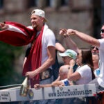Boston Celtics center Kristaps Porzingis waves to the crowd as he passes Copley Square during the duck boat parade to celebrate the 18th Boston Celtics NBA championship on Friday, June 21, 2024. The Celtics defeated the Dallas Mavericks in Game 5 of the NBA Finals.
