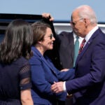 President Joe Biden Greets Massachusetts Gov. Maura Healey, center, as Boston Mayor Michelle Wu, left, watches, as he arrives on Air Force One at Boston-Logan International Airport, Tuesday, May 21, 2024.