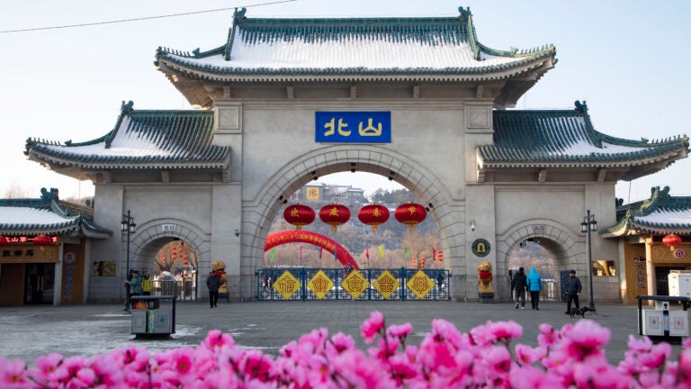 Tourists walk past a gateway with the name "Beishan" seen at the Beishan Park in northeastern China's Jilin province.