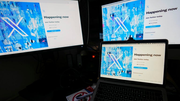 Computer monitors and a laptop display the X, formerly known as Twitter, sign-in page.
