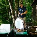 Will McLane loads a block of ice onto a wheelbarrow at Rockywold Deephaven Camps.