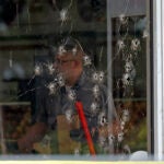 Damage can be seen to a front window law enforcement officers work the scene of a shooting at the Mad Butcher grocery store in Fordyce, Ark.