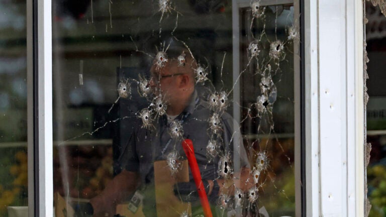 Damage can be seen to a front window law enforcement officers work the scene of a shooting at the Mad Butcher grocery store in Fordyce, Ark.