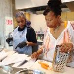 Glorya Fernandez (right) teaches a student how to cook black-eyed pea fritters at the Roxbury branch of the Boston Public Library.
