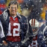 As snow falls around them, Patriots starting quarterback Tom Brady (left) and head coach Bill Belichick (right) laugh as they watch the replay on the scoreboard of the celebration technique of backup quarterback Brian Hoyer (8, backround between them) following his third quarter touchdown. The New England Patriots vs. the Tennessee Titans at Gillette Stadium.