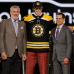 Dean Letourneau, center, poses after being selected by the Boston Bruins during the first round of the NHL hockey draft Friday, June 28, 2024, in Las Vegas.