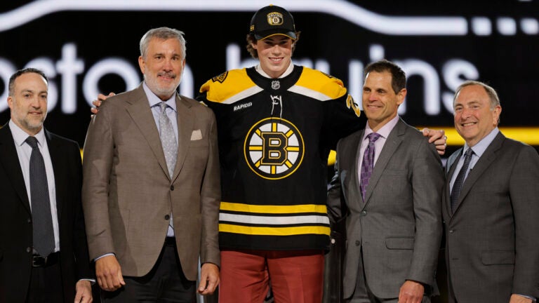 Dean Letourneau, center, poses after being selected by the Boston Bruins during the first round of the NHL hockey draft Friday, June 28, 2024, in Las Vegas.