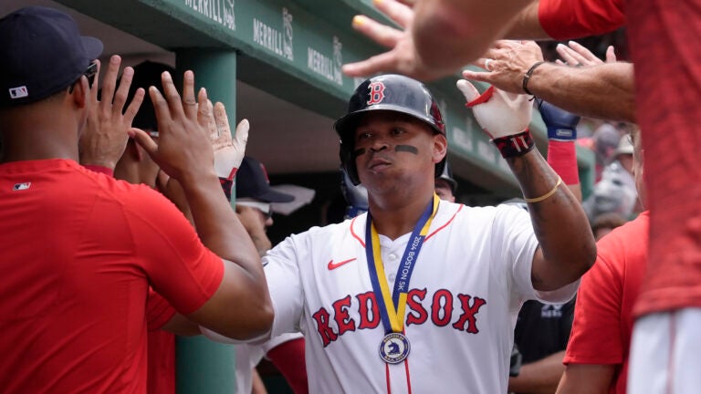 Rafael Devers of the Red Sox celebrates with teammates in the dugout after scoring on his two-run home run in the first inning.