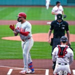 Philadelphia Phillies designated hitter Kyle Schwarber celebrates his solo home run on the first pitch of the game by Boston Red Sox's Kutter Crawford, rear.