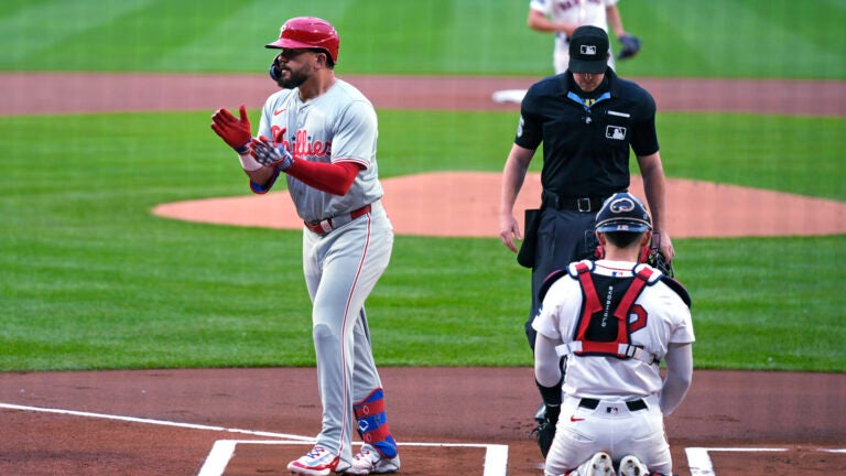 Philadelphia Phillies designated hitter Kyle Schwarber celebrates his solo home run on the first pitch of the game by Boston Red Sox's Kutter Crawford, rear.