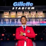 Tom Brady stands on the center stage under the looming superbowl banners as he gets a standing ovation at the end of the ceremony. Former New England Patriots quarterback Tom Brady was inducted into the Patriots Hall of Fame during a ceremony at Gillette Stadium.