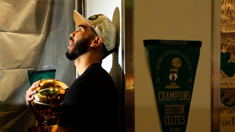 Boston Celtics forward Jayson Tatum holds the Larry O'Brien championship trophy in the locker room after winning the 2024 NBA Finals over the Dallas Mavericks at TD Garden on Monday, June 17, 2024.