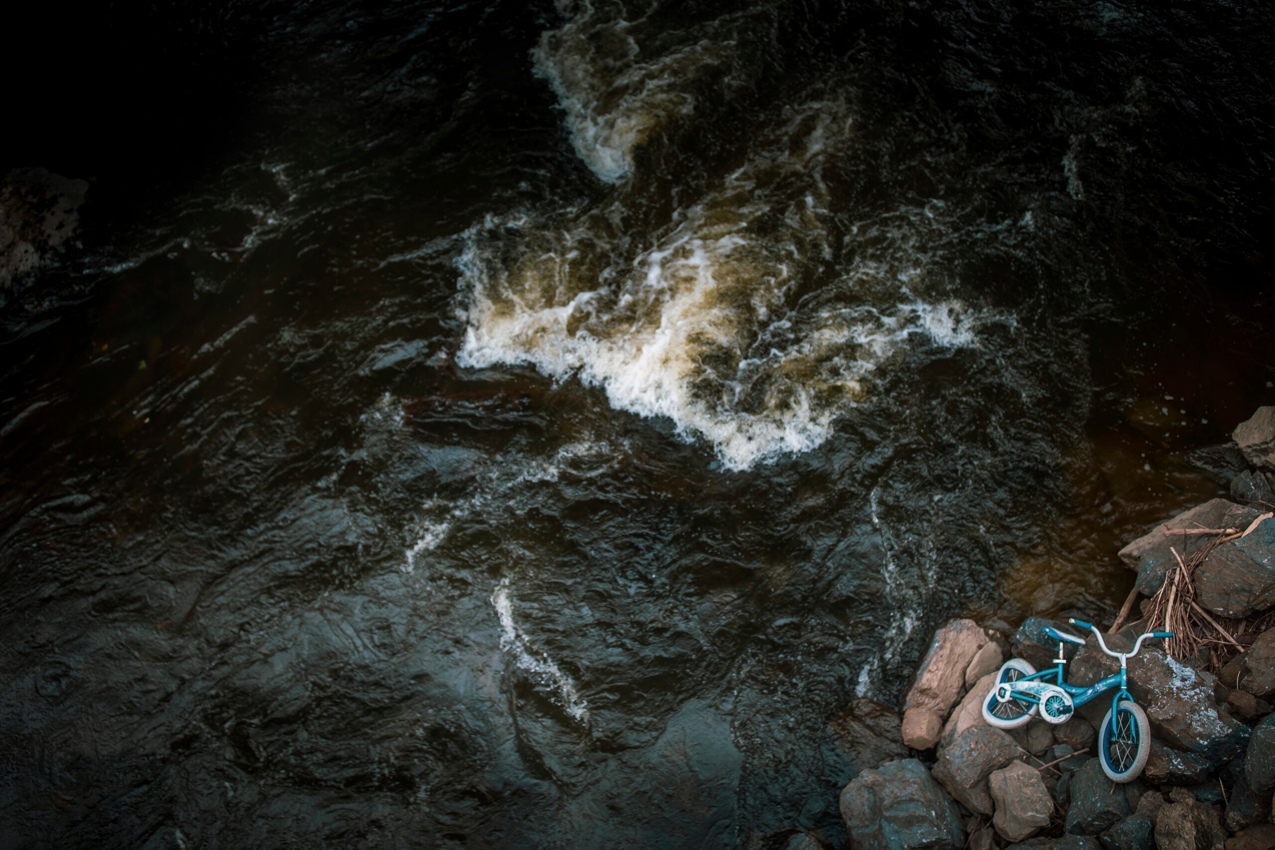 A kid's bike lies beside the shore of the Winooski River which runs through Montpelier, Vt.